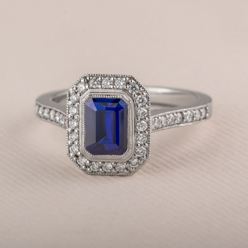 Blue sapphire and diamond cluster engagement ring in platinum