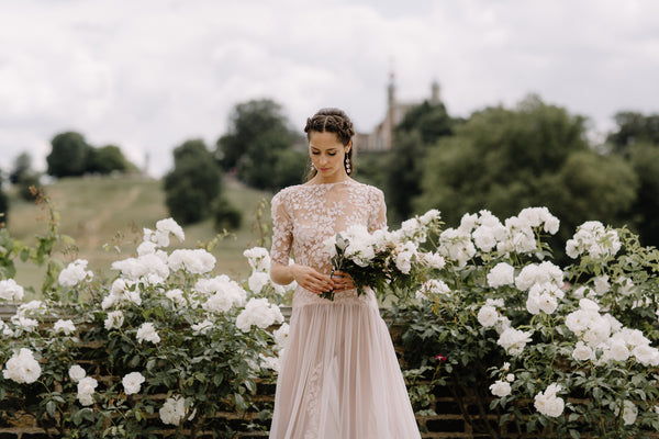 Beautiful bride in wedding dress with white rose bushes in countryside