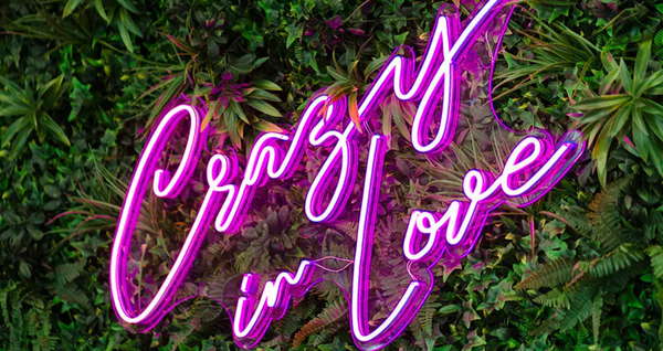 Crazy in love pink neon lights with green leaves backdrop