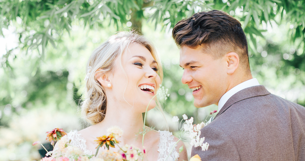 Bride and groom smiling underneath a fir tree