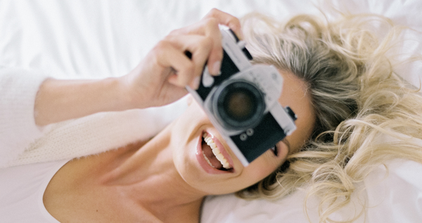 Bride lying in a bed with a camera