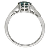 Platinum engagement ing with a round green sapphire centre stone, diamond clusters in a leaf-inspired design. Made in London