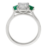 Three stone platinum ring with emerald cut lab diamond centre and natural emerald side stones. Made in the UK