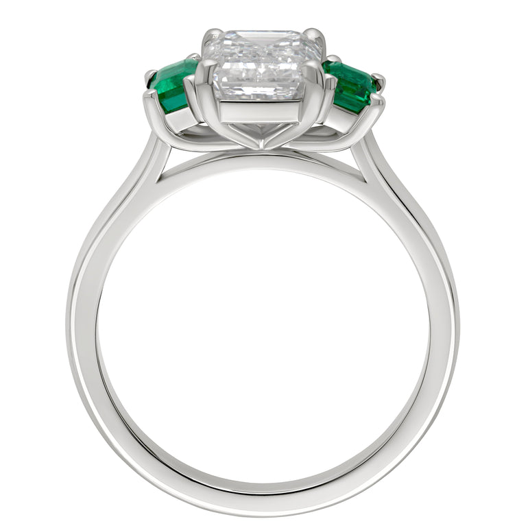 Three stone platinum ring with emerald cut lab diamond centre and natural emerald side stones. Made in the UK