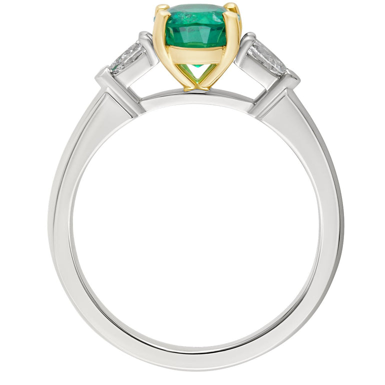 Oval emerald engagement ring showing yellow gold claw setting, diamond side stones and white metal band. Made in Hatton Garden