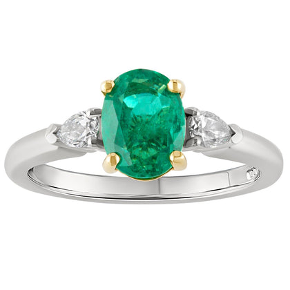 Oval emerald engagement ring set in in platinum with yellow gold claws and pear-shaped diamond side stones. Made in London