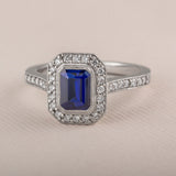 Blue sapphire and diamond cluster engagement ring in platinum