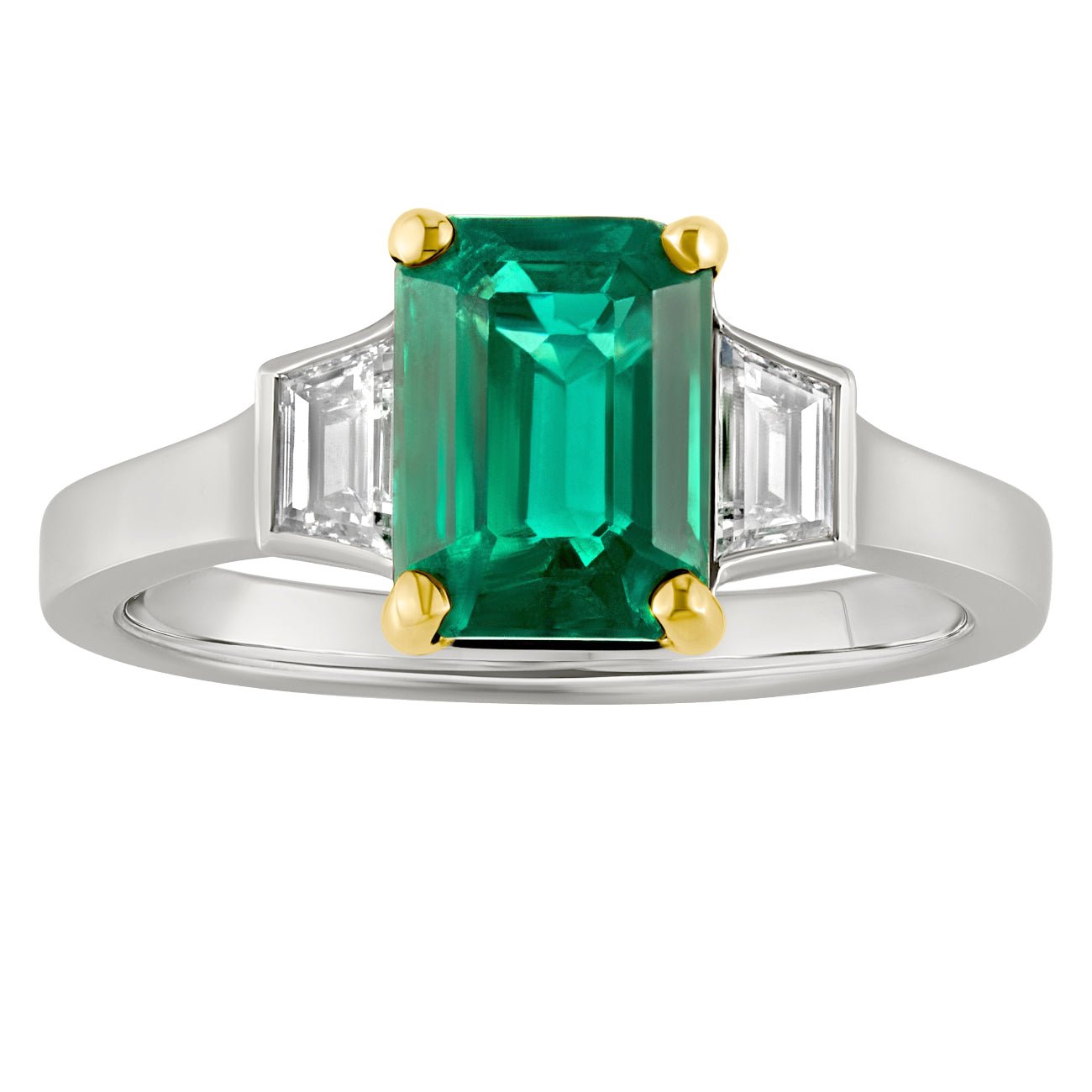 emerald and diamond trilogy ring with emerald-cut emerald framed by trapezoid diamonds on each shoulder. Two tone platinum and 18ct yellow gold. Made in The UK