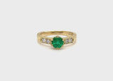 Emerald engagement ring with engraved yellow gold band and diamonds