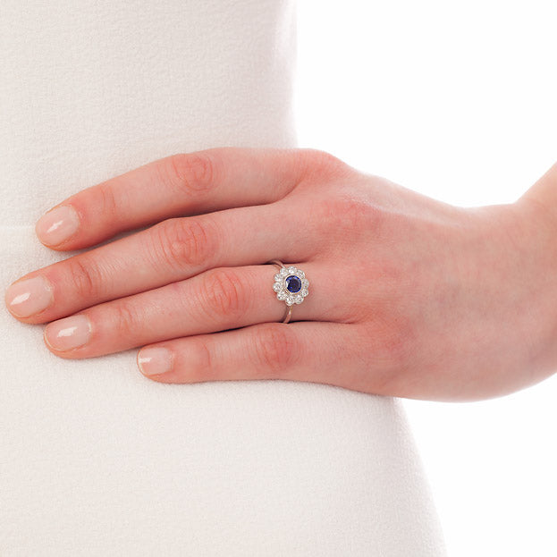 Sapphire ring with surrounding diamonds on hand