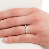 Curved diamond wedding ring with diamonds set in white gold band on hand