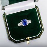 Emerald-cut blue sapphire ring with baguette diamond band in box
