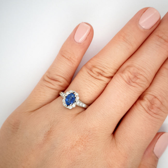 Oval blue sapphire and diamond cluster ring on hand